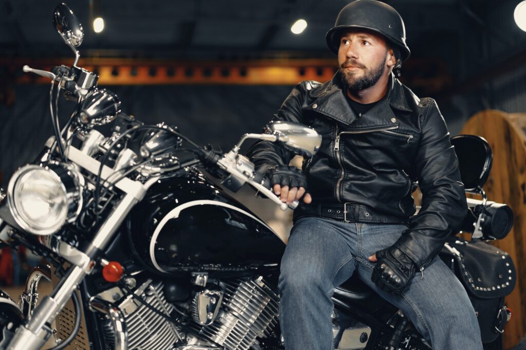 Biker man in leather jacket and helmet sitting on his motorcycle