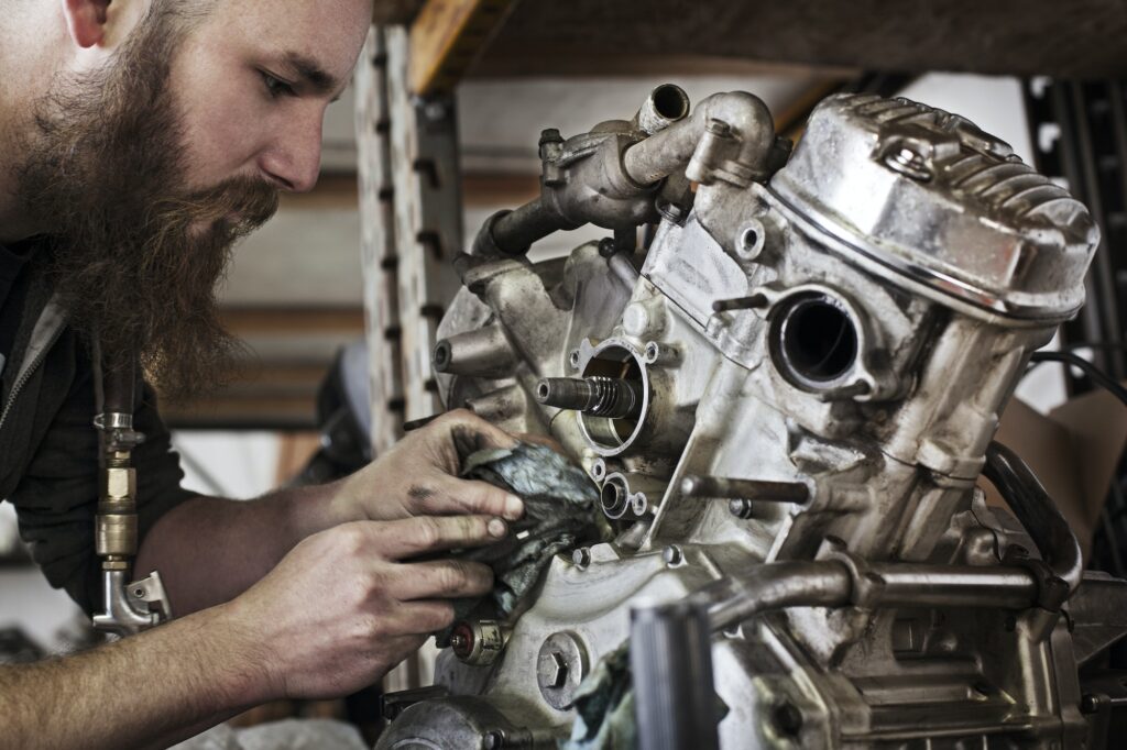 Cropped Image Of Mechanic Working On Motorcycle Engine At Shop